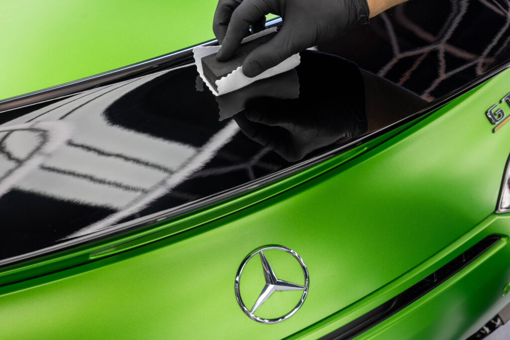 Auftragen von Keramikversiegelung auf schwarzem Heckspoiler von Mercedes
