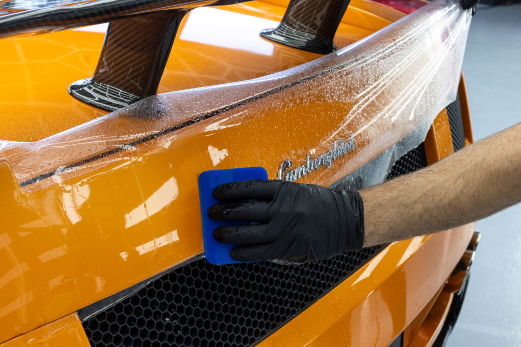 Aufziehen von PPF Schutzfolie auf Heck von orangenem Lamborghini